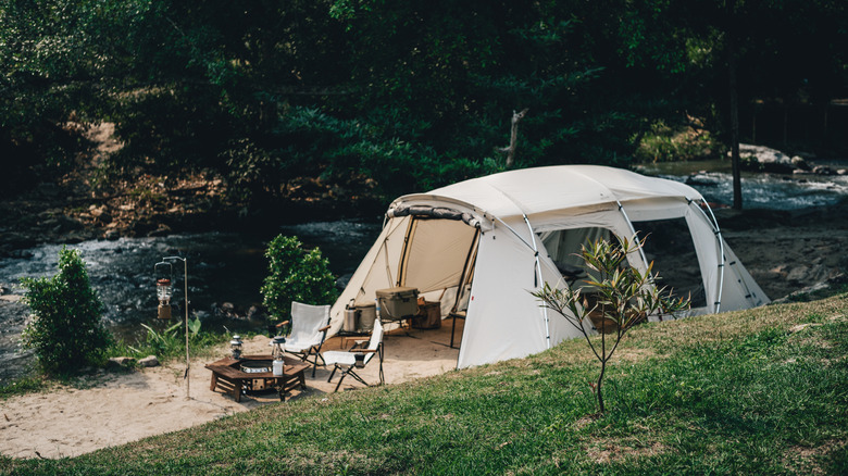 A white Snow Peak tent set up next to a stream