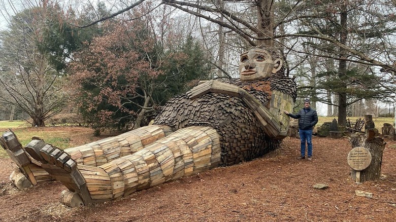 Mama Loumari sculpture laying back against a tree in Bernheim Forest