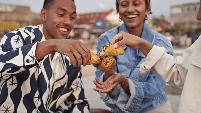 Three friends eating tacos together