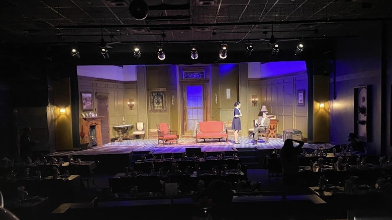 A stage performance with seats and tables at Myers Dinner Theatre