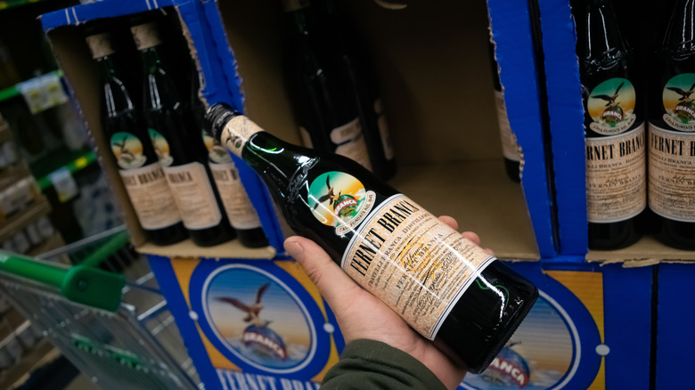 Hand holds Fernet Branca bottle in store