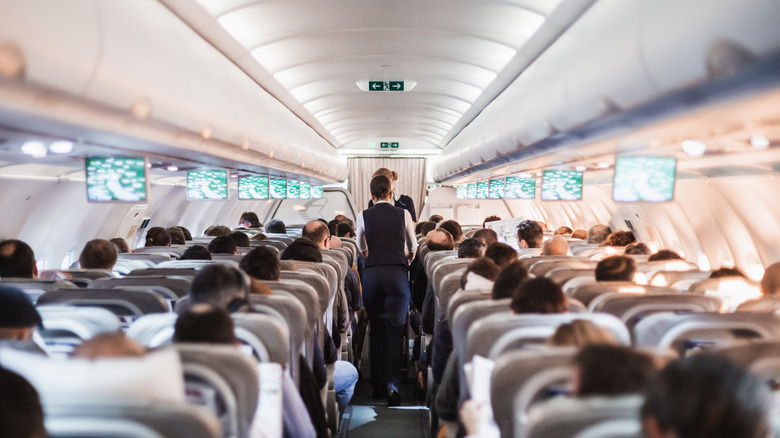 A flight full of people with flight attendants in the aisle