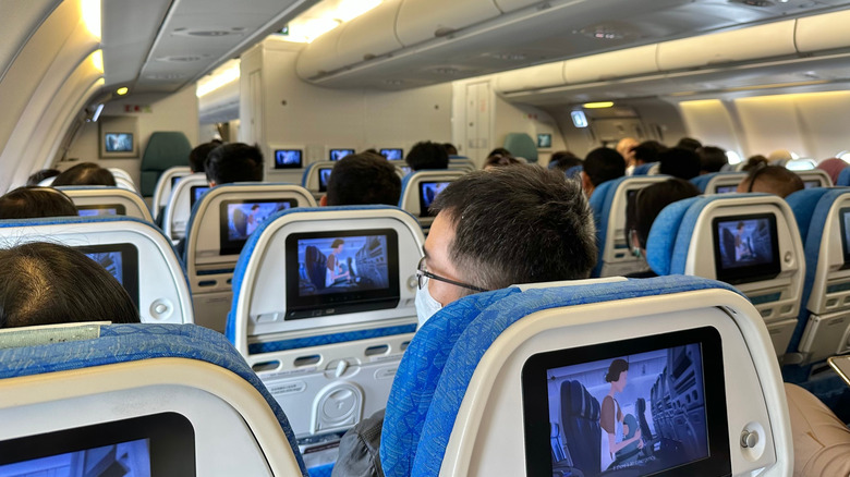 Passengers in the economy cabin watching an in-flight program