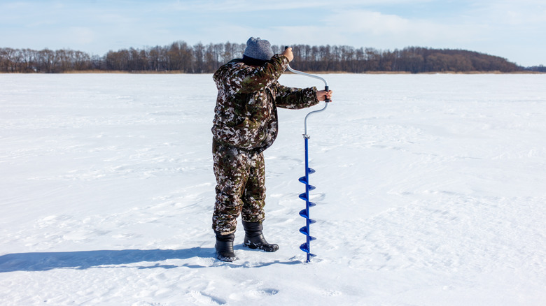 A person using an ice auger to test thickness of ice