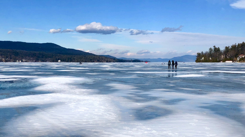 Three people walking across frozen Adirondack lake