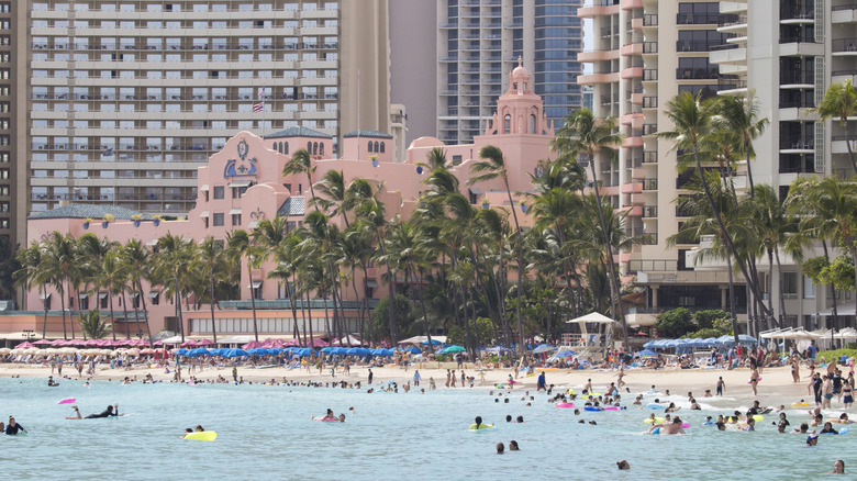 Tourists on Oahu, Hawaii visit Waikiki Beach outside a resort hotel