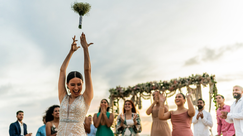 A bride throwing her bouquet at guests
