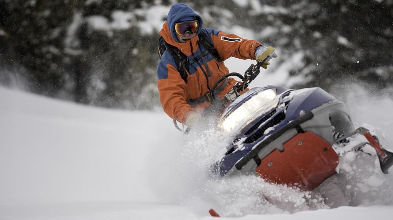 A man in orange snowmobiling