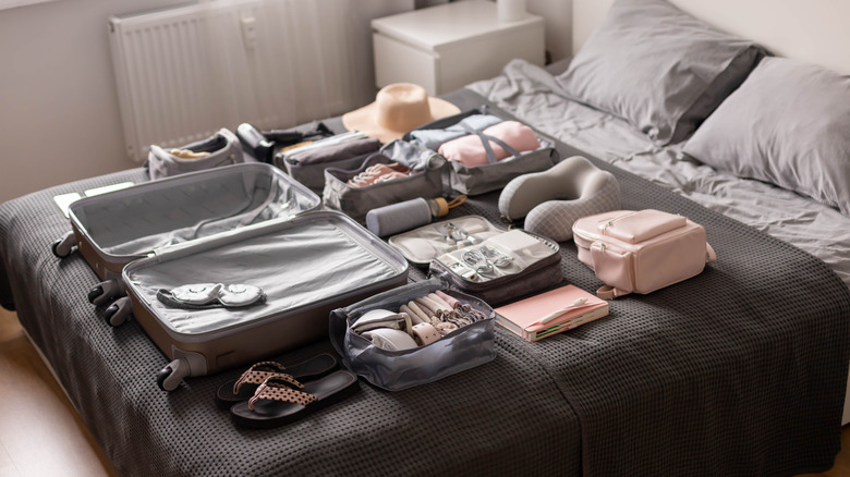 A suitcase and items arranged on a bed