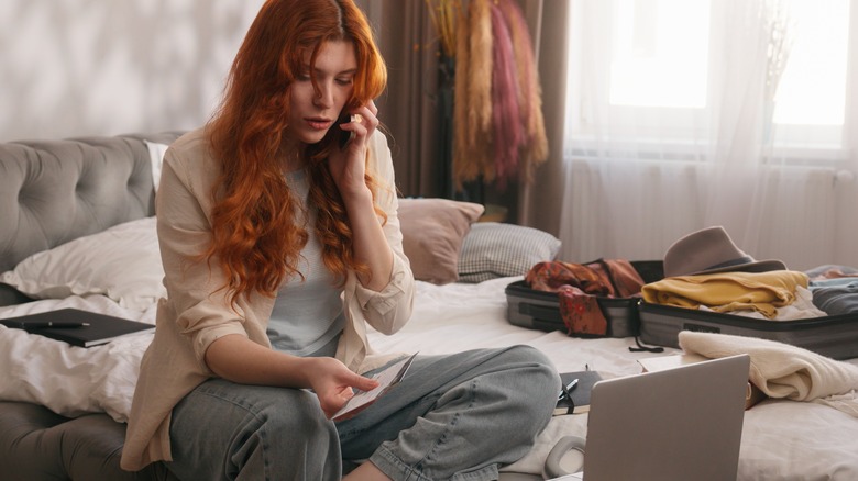 woman on phone with passport and laptop