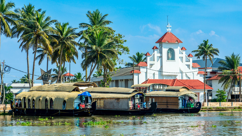 A colonial church and houseboats seen from the water in Alappuzha, India