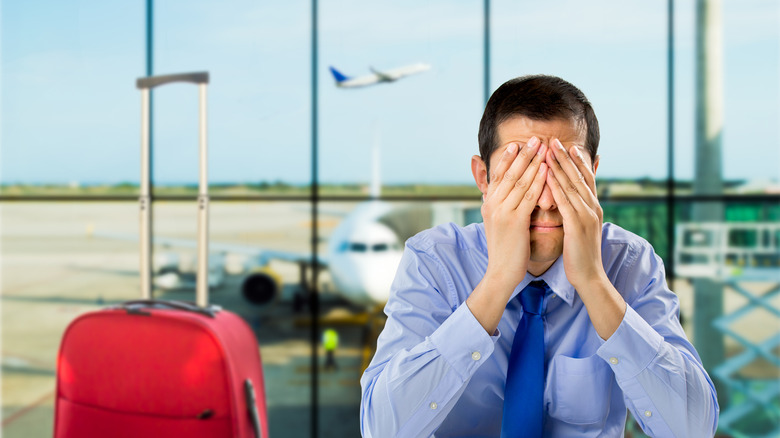 Crying businessman with delayed flight at an airport