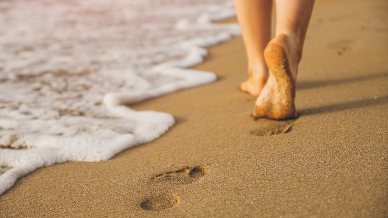 Person with bare feet walking on the beach