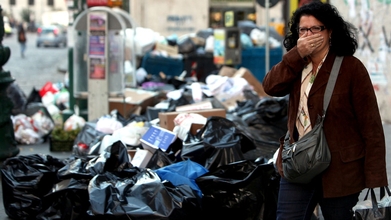 A woman passing through piles of trash in Naples