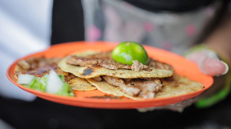 Thin slices of grilled beef on corn tortillas with lime on top