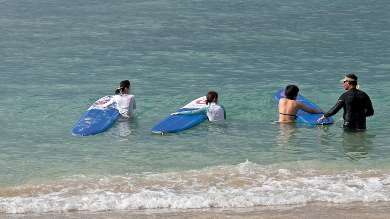 Women getting surfing lessons off Honolulu