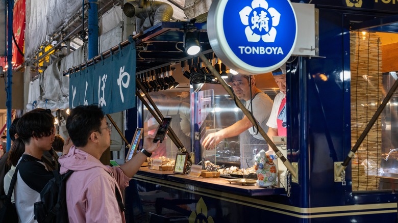 People ordering food at stall in Tsukiji Outer Market in Tokyo