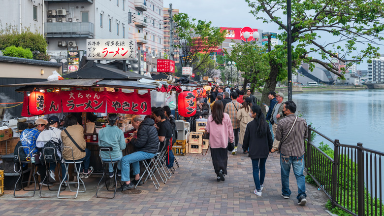 A street filled wtih yatai stalls, customers, and pedestrians in Fukuoka