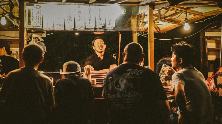 Shopowner speaking with customers in a Fukuoka yatai