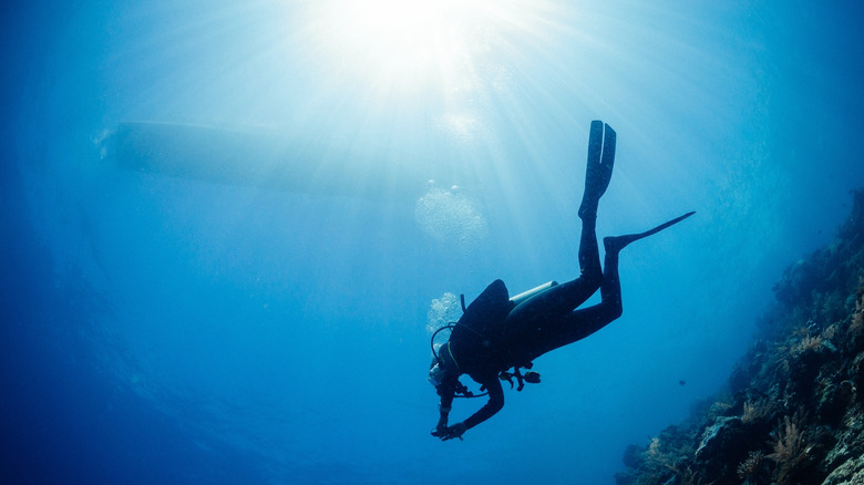 Scuba diver underwater with boat waiting