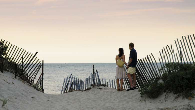 Couple standing by wooden fence on Montauk beach