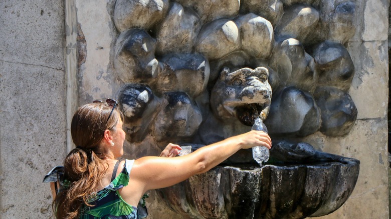 Filling water bottle at Roman fountain