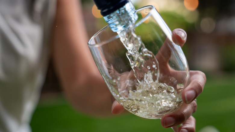 A woman pouring a glass of Vinho Verde wine