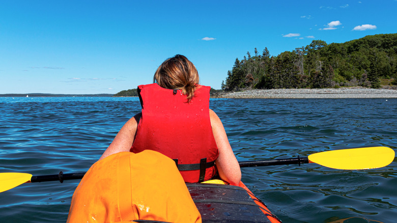 Woman paddles a kayak around the Porcupine Islands in Maine