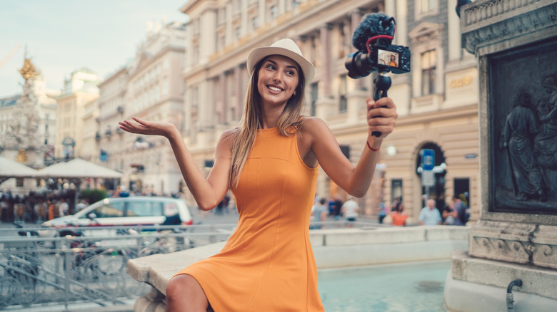 Vlogger sits on fountain in a European city to film content