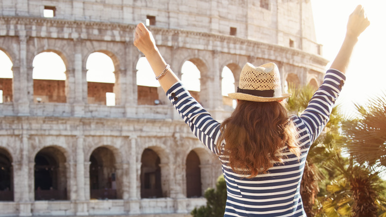 Woman with hands raised by the Colosseum