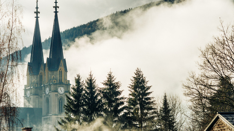 Spires and trees against mountain fog in Admont, Austria