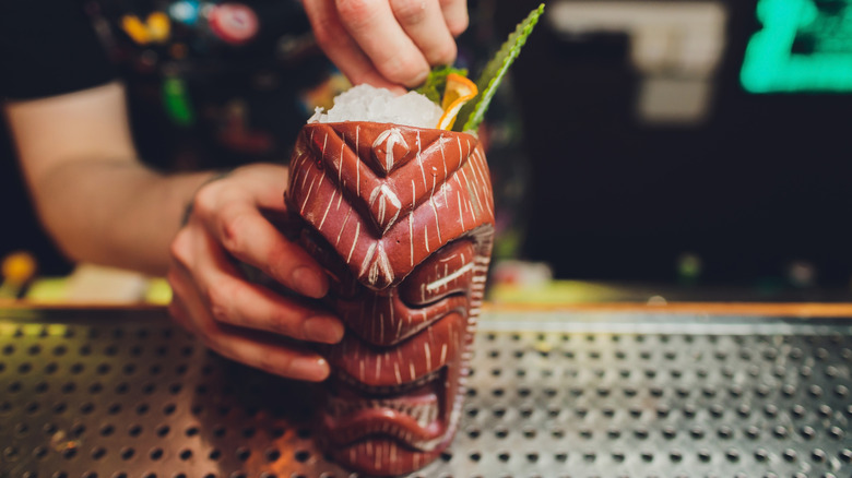 Hand mixing drink in tiki glass