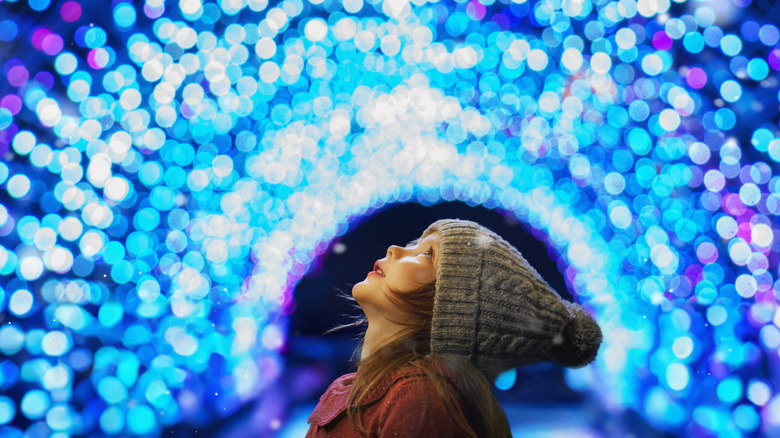 Little girl looking up at blue holiday lights