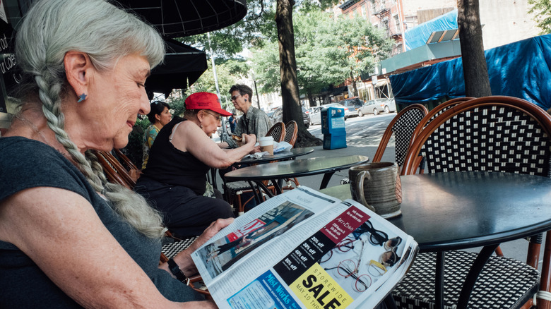 A woman reading a magazine at an outdoor cafe in New York