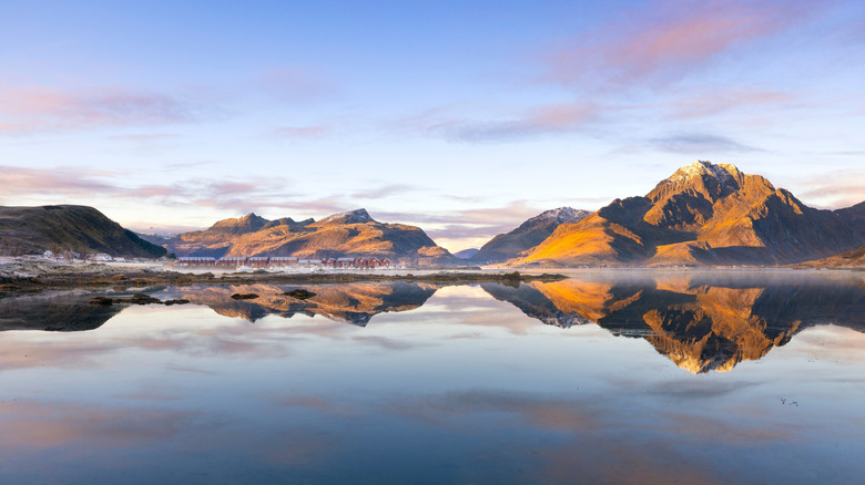 Mountain peaks reflected in the sea under a purple-tinted sky