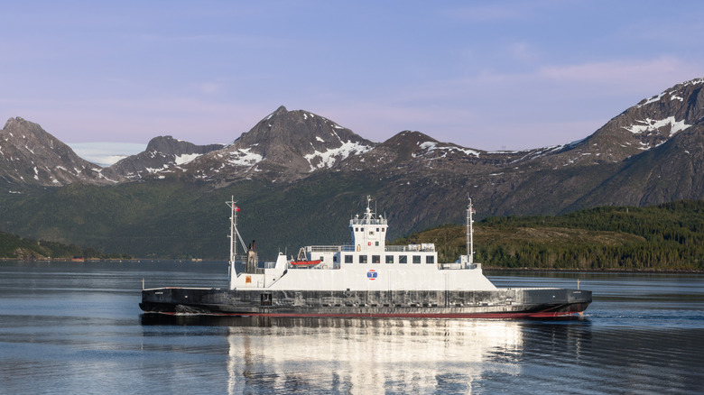 A white Arctic ferry with a slightly snowy, mountainous background