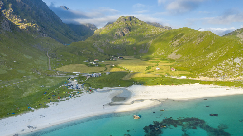 Haukland Beach with white sand, turquoise water, and green mountain backdrop