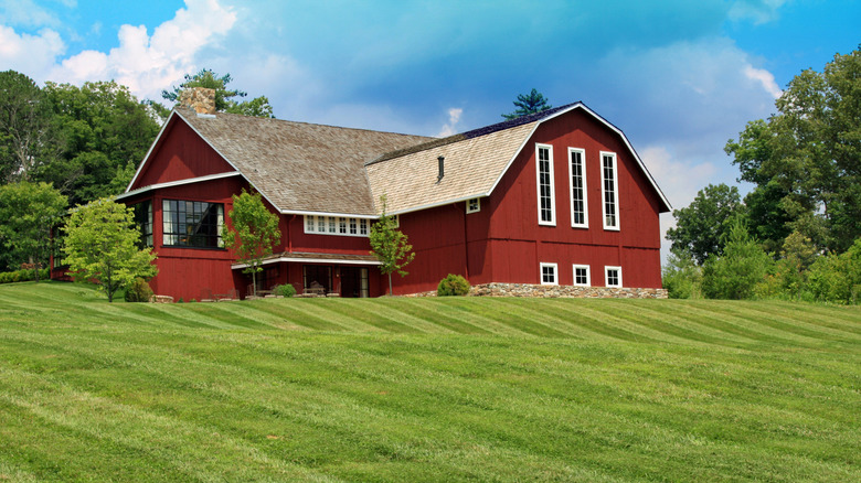 A large red barn on a hilltop overlooking rolling green lawns at Blackberry Farm