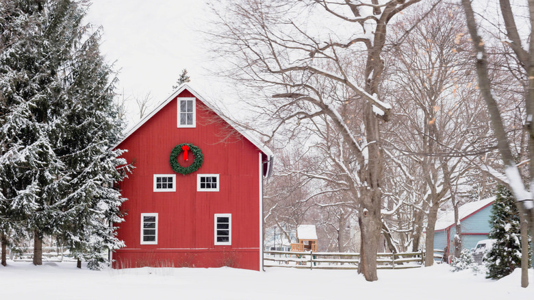 Snowy scene with red barn with Christmas wreath