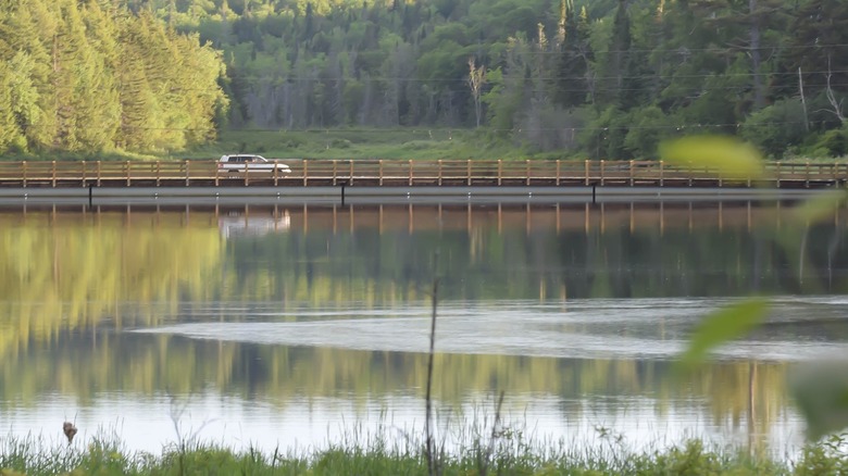 Car driving over floating bridge on water