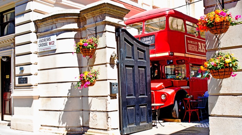 Red bus hidden in a courtyard seen through a black gate at the Old Bank of England pub