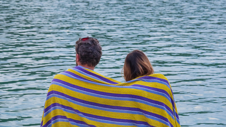 couple with towel by water