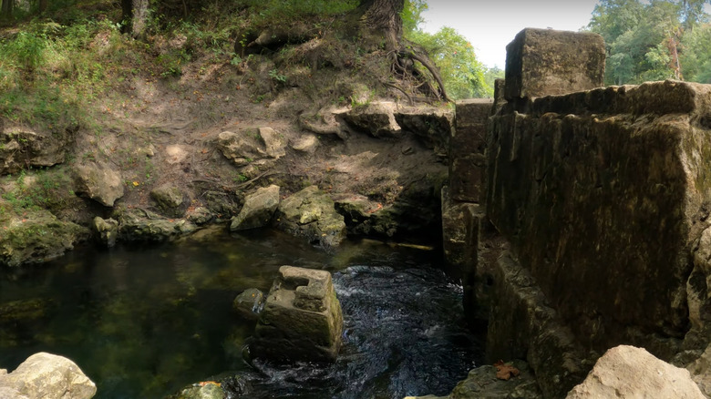 Fresh water flowing from the spring, past ruins of old buildings along a bank