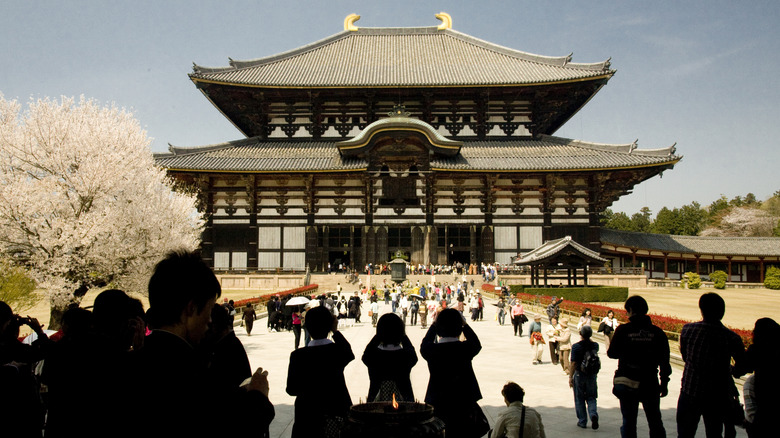 Visitors take photos of a giant two story wooden temple in Japan