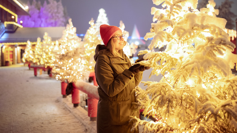 Woman enjoying a snowy, lighted Christmas tree