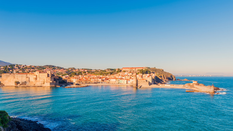 a village skyline bookended by a medieval fort and a church on a sandy beach