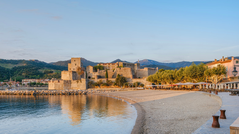 a medieval castle sits on a small crescent-shaped beach