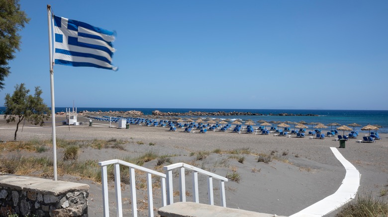 Greek flag and sun loungers on Monolithos Beach