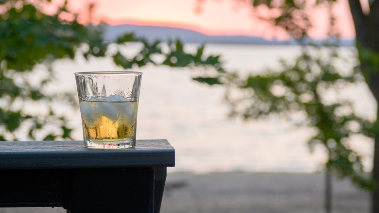 A glass of whiskey on a chair with Lake Pepin in the background