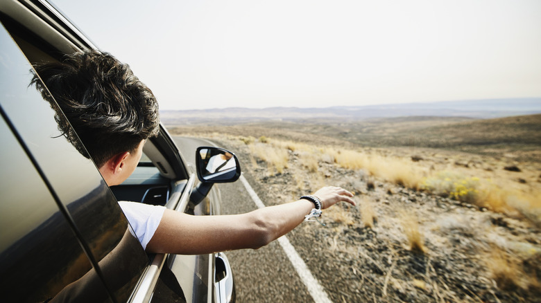 Roadtrip passenger with the window open reaching outside